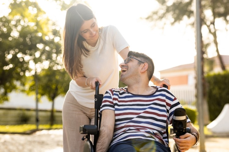 A smiling individual with disability receiving support from a carer in a Supported Independent Living