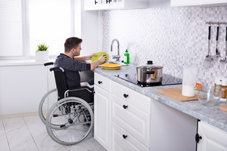 Man with disabililty washing plate while on wheel chair