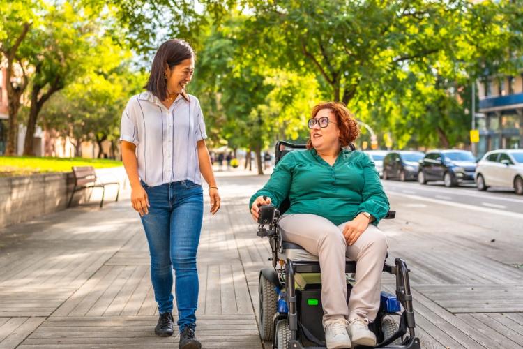 Community access member walking with a woman in a wheelchair